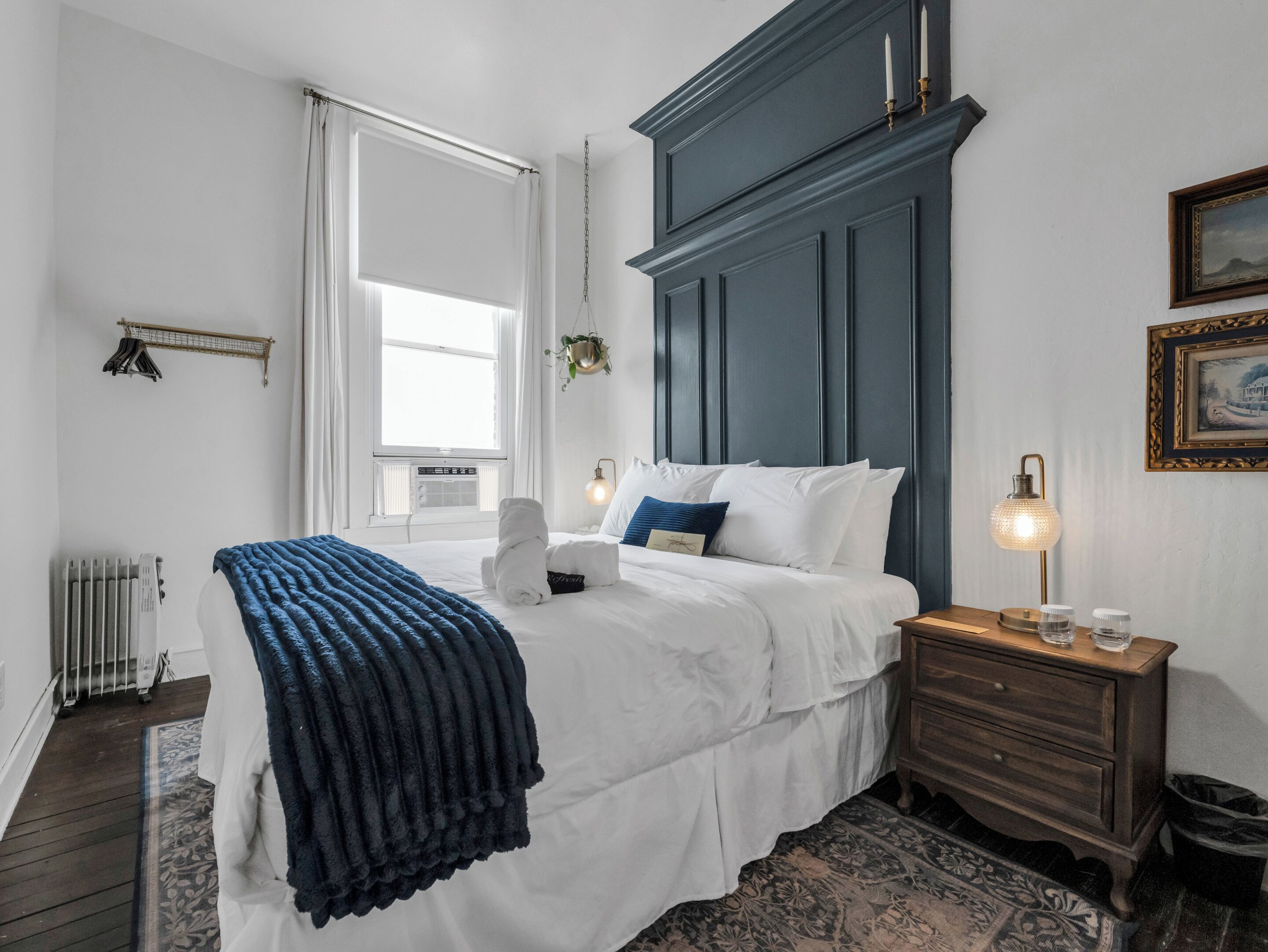 A bedroom with a bed, a nightstand, a radiator, and a window.