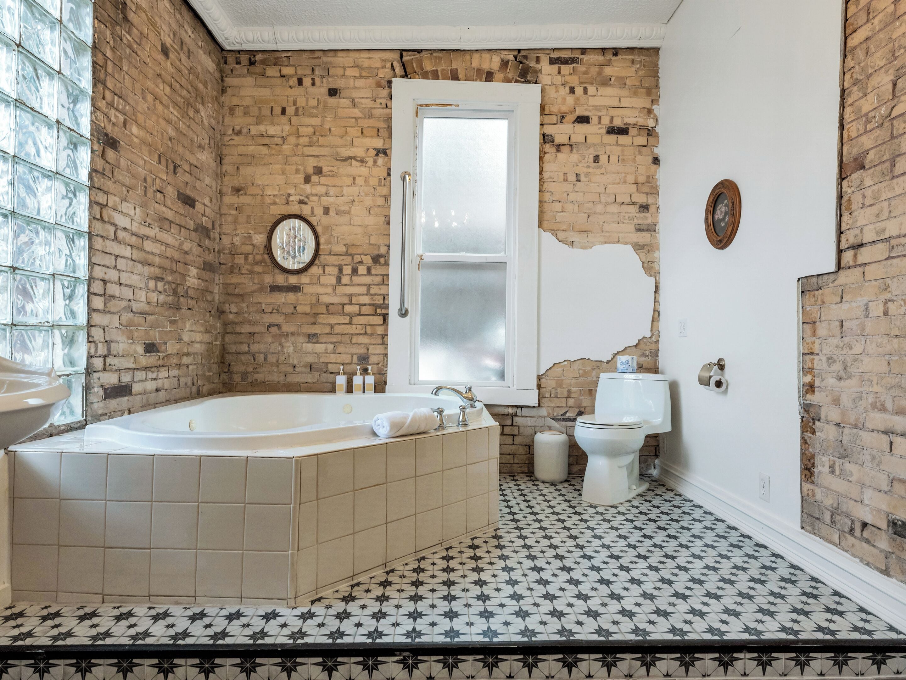 A bathroom with a bathtub, toilet, and a window with a mirror.