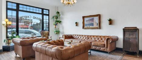 A spacious living room with a large window, leather sofas, a chandelier, and a patterned rug.