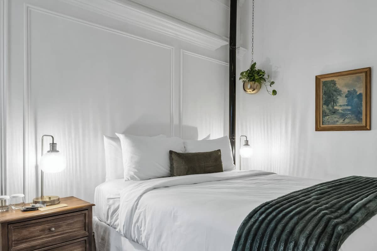 Une chambre bien rangée, avec un lit, des tables de chevet et une plante suspendue.