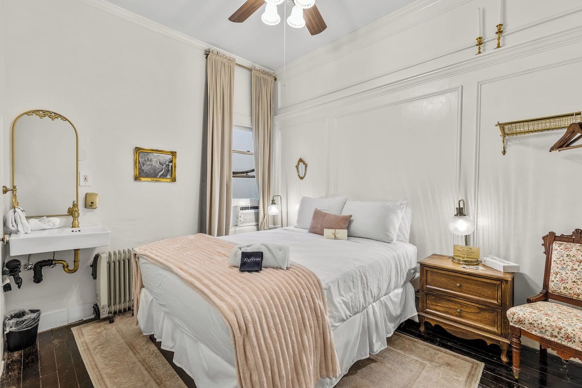 Une chambre à coucher bien rangée, avec un lit, une table de chevet, une lampe et une chaise.