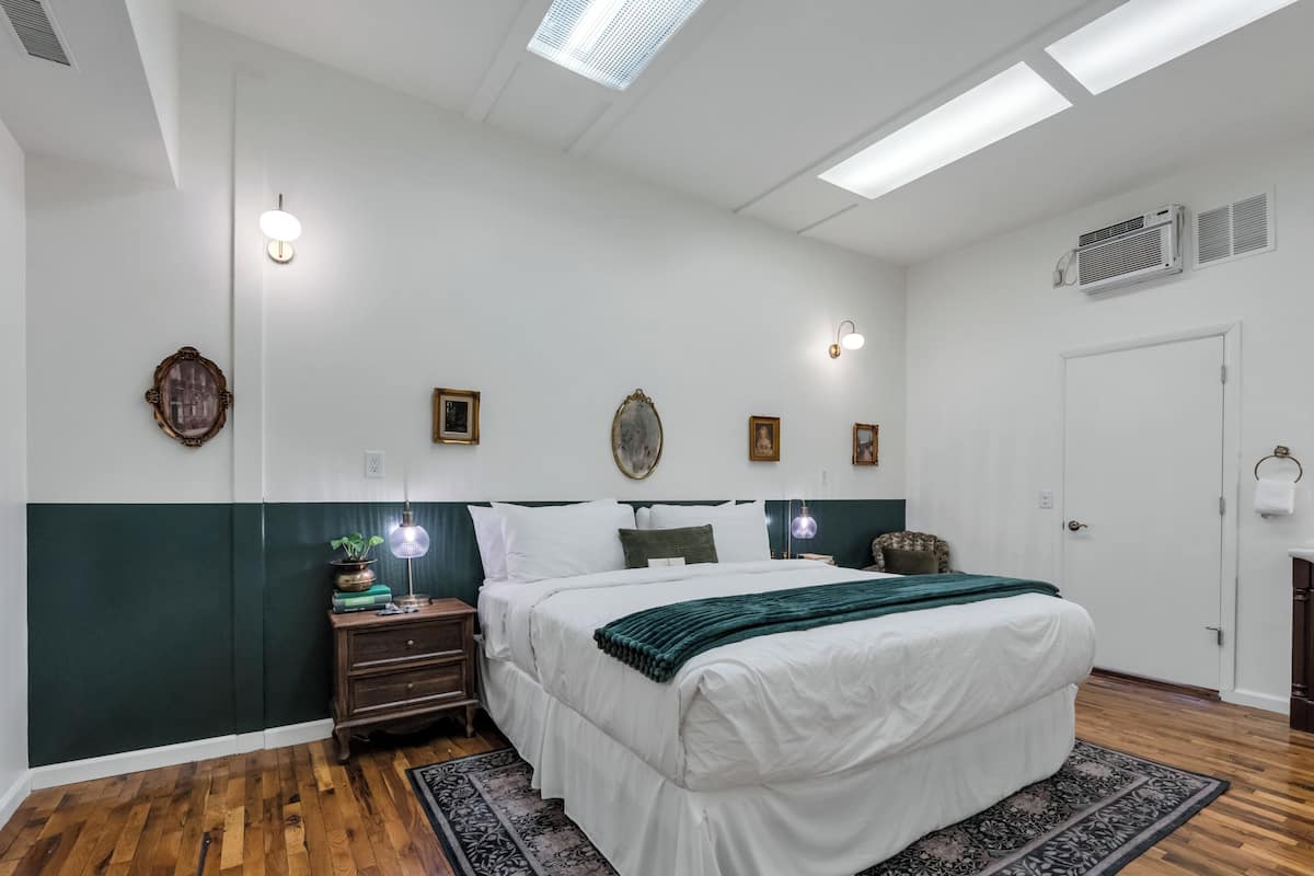 Une chambre à coucher comprenant un lit, des tables de chevet, des lampes fixées au mur et une fenêtre.