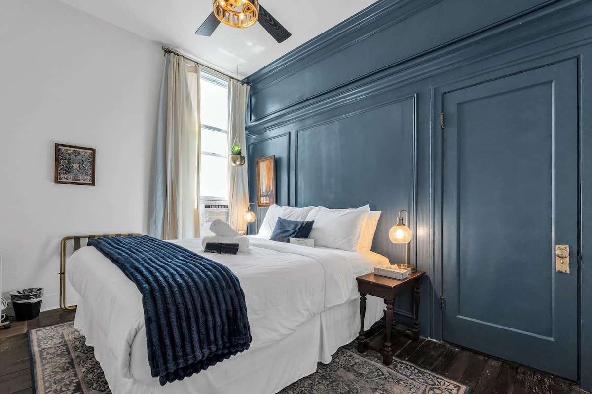 Une chambre à coucher avec un lit, une table de chevet et un ventilateur de plafond.