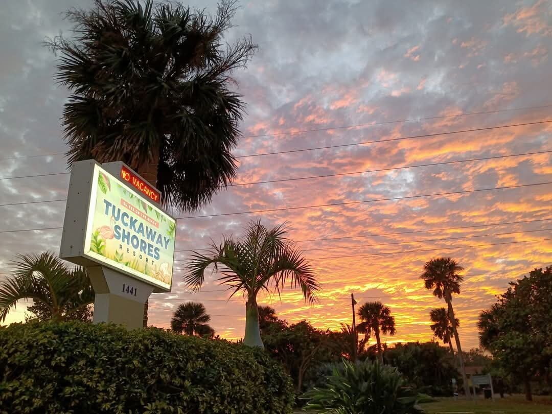 A sign for Tuckaway Shores Resort with a sunset in the background.