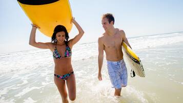 Dos personas caminando por la playa con tablas de surf.
