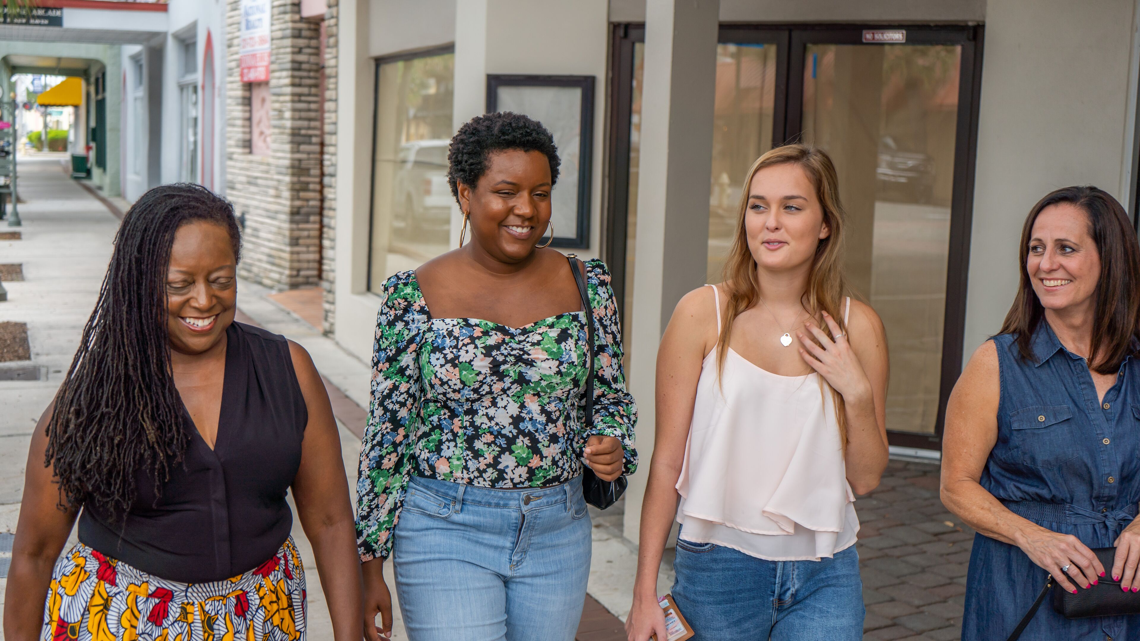 Four individuals walking on a sidewalk.