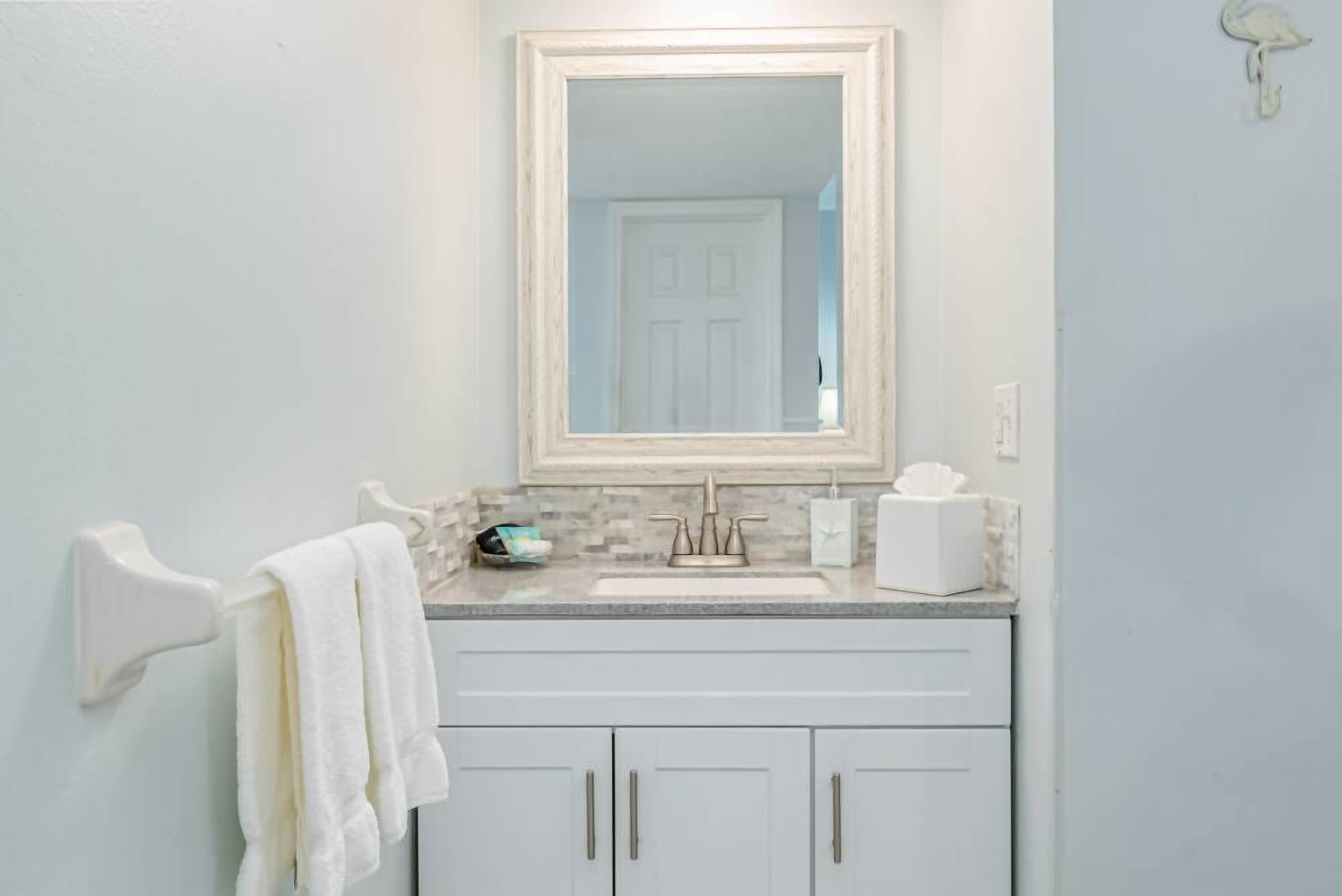 A bathroom with a white sink, a mirror, and a towel rack.