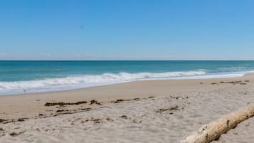 A beach with clear skies, gentle waves, and a log on the sand.