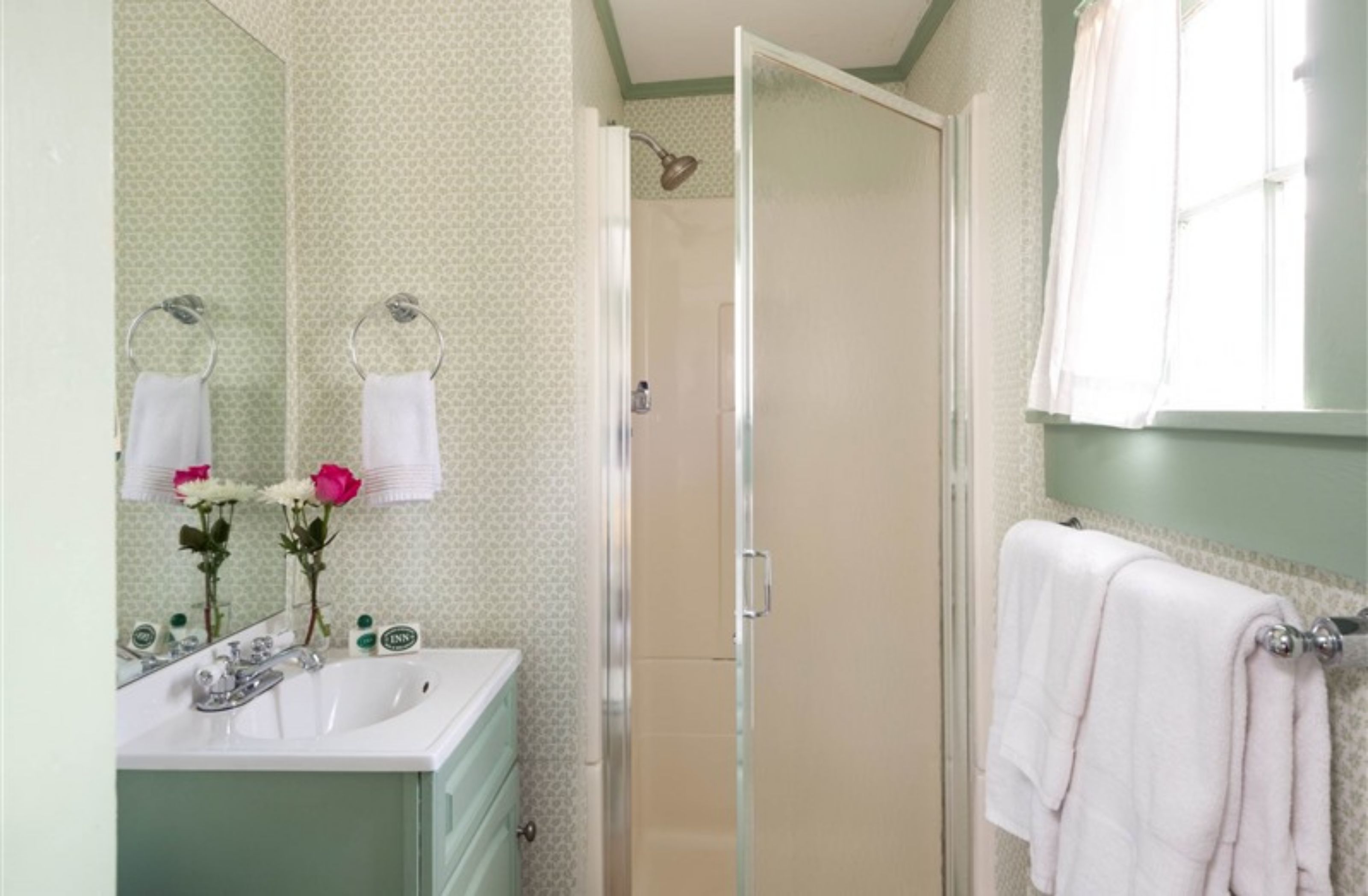 A bathroom with a sink, mirror, and shower.