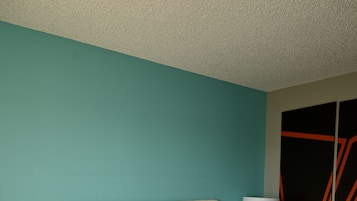 A hotel room with a large bed, a headboard, a bedside table with a lamp, and a wardrobe with a mirror.