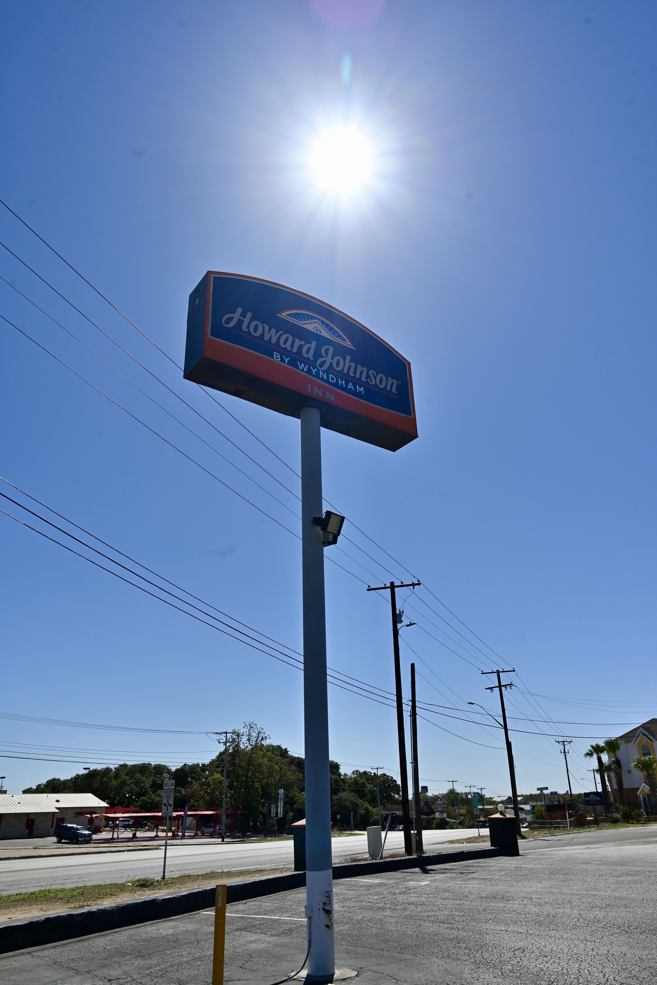 Un letrero de Howard Johnson con un cielo azul despejado y el sol al fondo.
