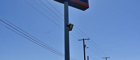 Un letrero de Howard Johnson con un cielo azul despejado y el sol al fondo.
