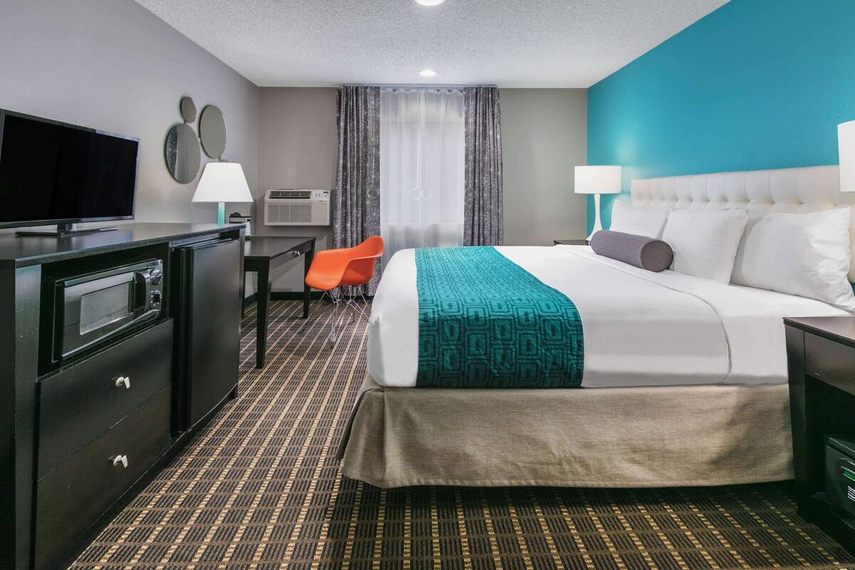 A hotel room with a bed, a desk, a television, and a chair.