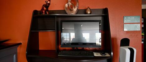 A desk with a Lenovo monitor, keyboard, and a soap dispenser.