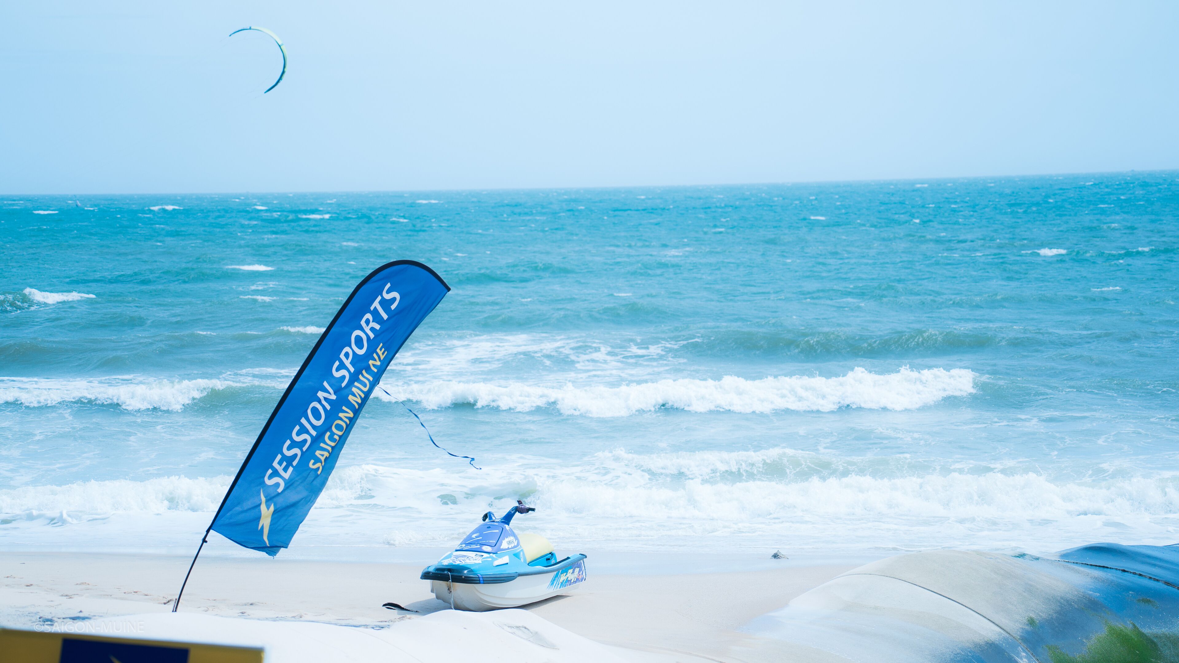 Een strand met een blauwe vlag, een jetski en de oceaan.