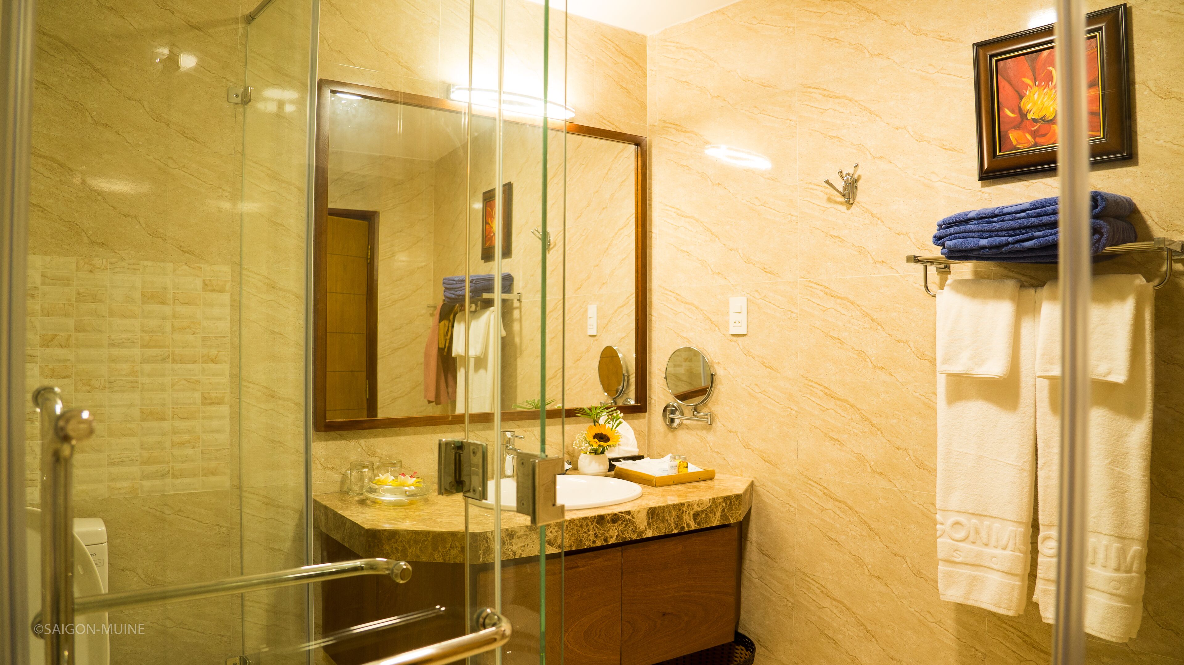Un baño moderno con cabina de ducha de vidrio, encimera de mármol y un espejo grande.