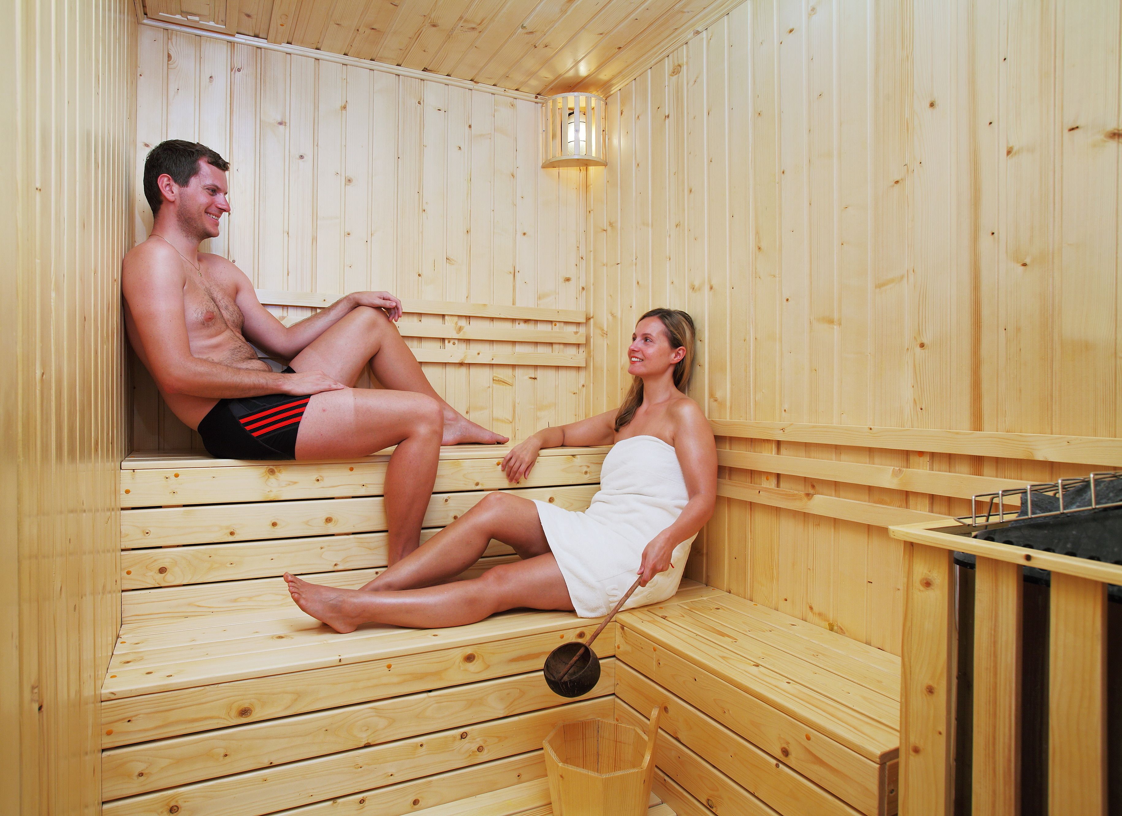 A sauna with wooden benches and a small bucket.