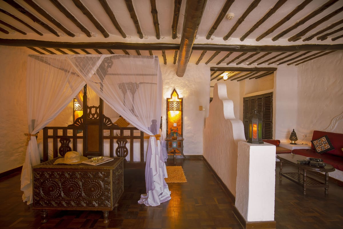 A traditional room with a bed, a small table, a sofa, and a decorative lamp.