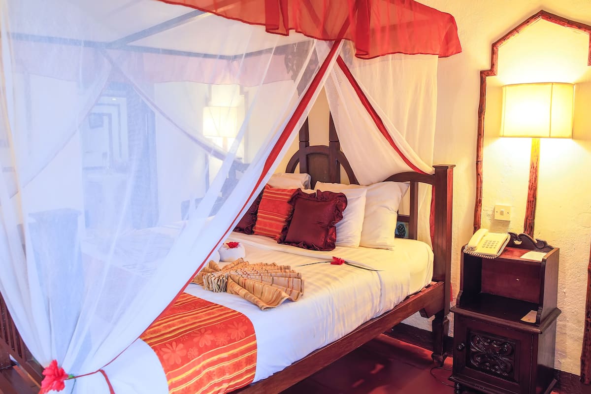 A bed with a canopy, a bedside table with a lamp, and a telephone.
