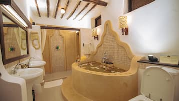 Bathroom features a bathtub, two sinks, and a toilet, with exposed beams and a mirror above the sinks.