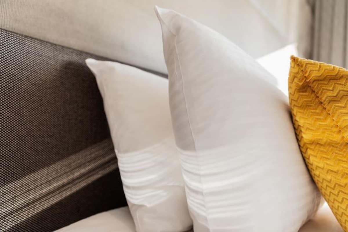 A bed with white and yellow pillows.