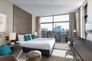 A hotel room with a large bed, a desk, a chair, and a TV. - Fraser Suites Sydney (Sydney)