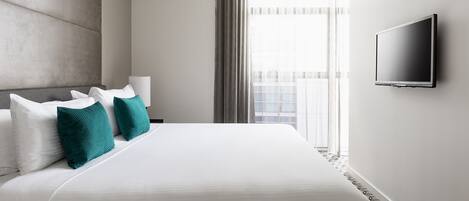 Habitación de hotel con una cama grande, televisión de pantalla plana en la pared y ventana con cortinas.