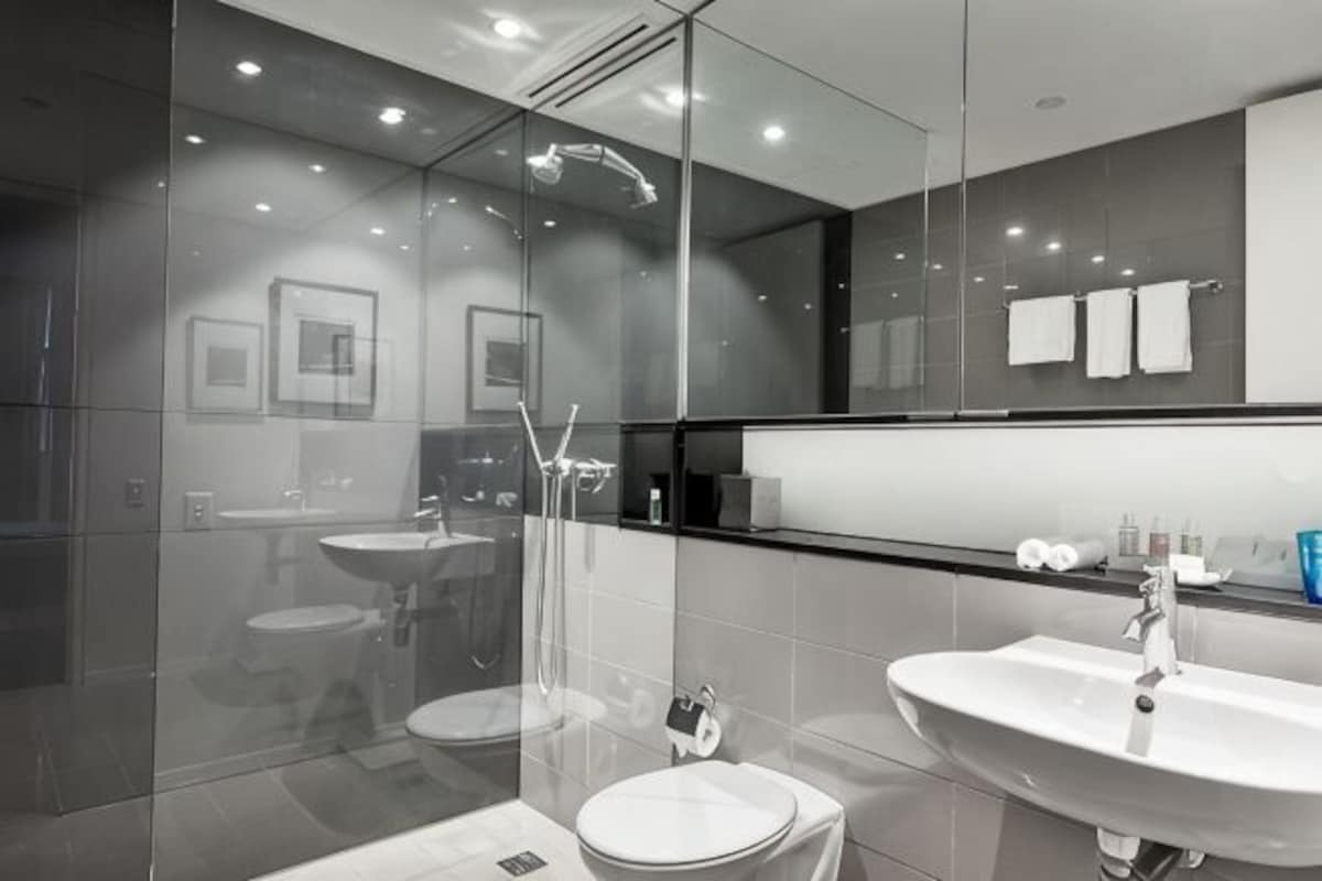 A modern bathroom with a glass-enclosed shower, two sinks, and a large mirror.