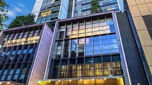 A modern hotel with a glass facade, a ground-level entrance with seating, and a visible sign for 'Frasers Suites'. - Fraser Suites Sydney (Sydney)