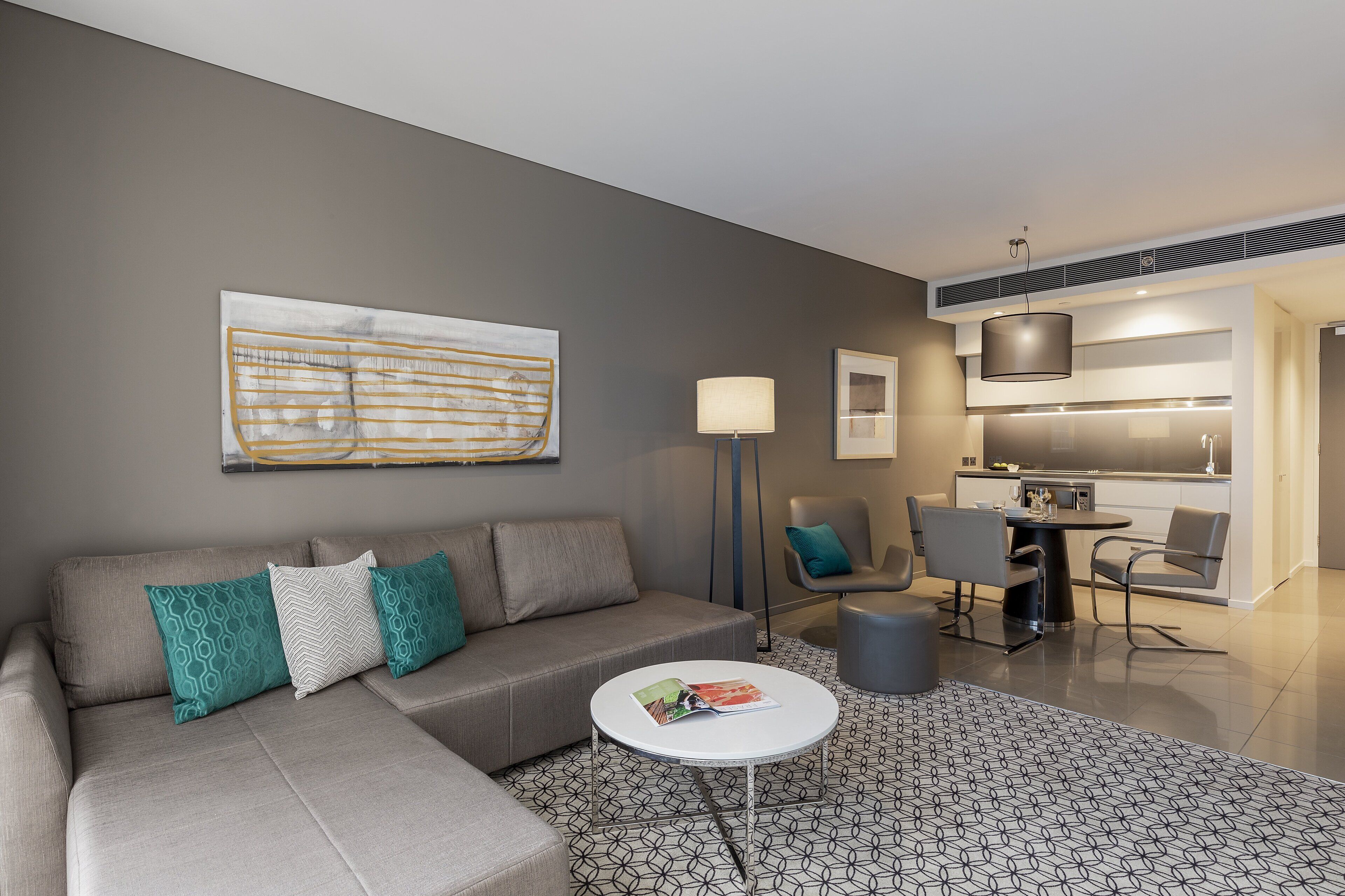 A modern living room with a sectional sofa, a coffee table, and a dining area with chairs and a table.