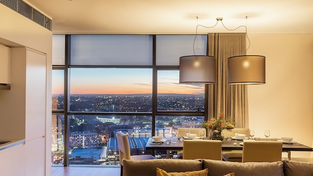 A modern dining area with a city view, large windows, and contemporary furnishings. - Fraser Suites Sydney (Sydney)