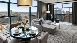 A modern hotel room with a panoramic city view, a dining area with a round table, and a cozy seating area with a sofa and armchairs. - Fraser Suites Sydney (Sydney)