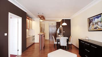 A modern kitchen with wooden cabinets, a dining area with a table and chairs, and a black cabinet with drawers.