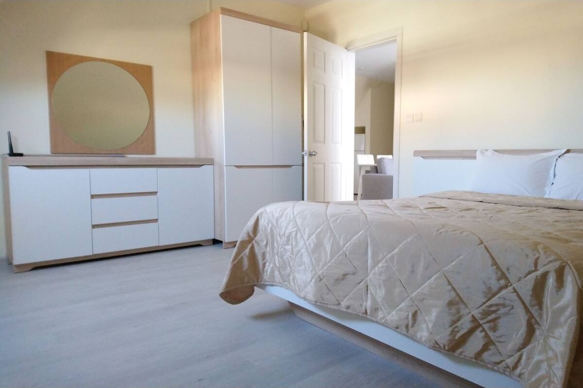 A bedroom with a bed, a wardrobe, and a mirror.