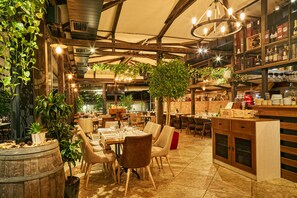 A restaurant with wooden beams, hanging plants, and a bar area with shelves of bottles. - Apartments Carrera (Sofia)