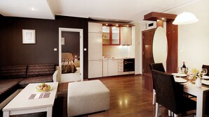 Un salon moderne avec un canapé, une table à manger dressée pour deux personnes et une cuisine en arrière-plan.