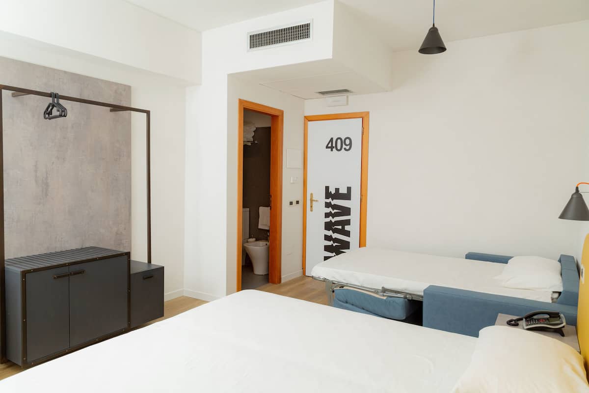 A bedroom with a bed, a wardrobe, a bathroom, and a door labeled "409 WAVE".
