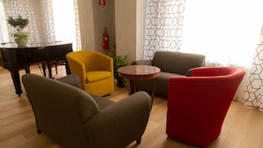 Una sala de estar moderna con un piano, un sillón rojo, un sillón amarillo y un sofá gris.