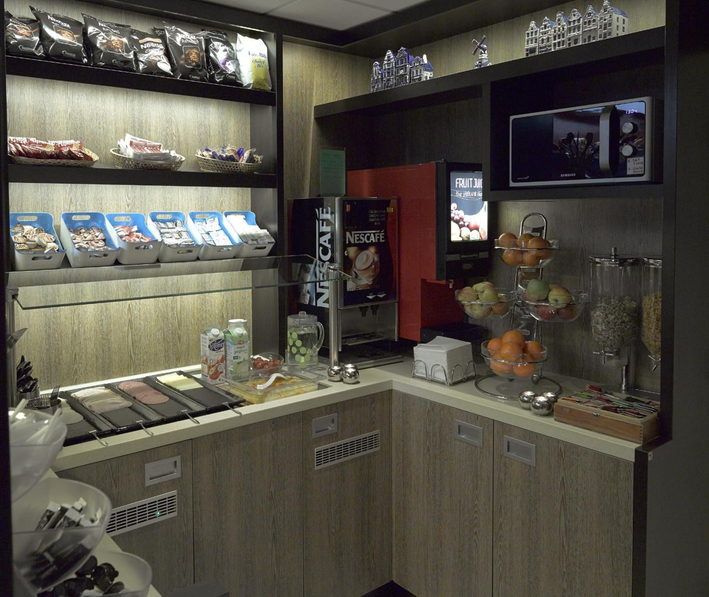 A coffee station with various coffee bags, a Nescafé display, and a fruit bowl.