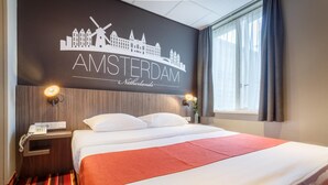 A hotel room with a bed, a nightstand, a lamp, a window with curtains, and a wall with a cityscape mural. - Hotel Mozart (Amsterdam)