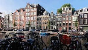 A row of historic buildings with a canal in the foreground. - Hotel Mozart (Amsterdam)