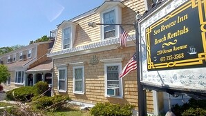 A two-story building with a sign for Sea Breeze Inn, including contact information and a beach view. - Sea Breeze Inn (Hyannis)