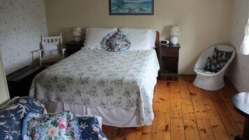 A bedroom with a bed, a chair, a nightstand, and a painting on the wall.