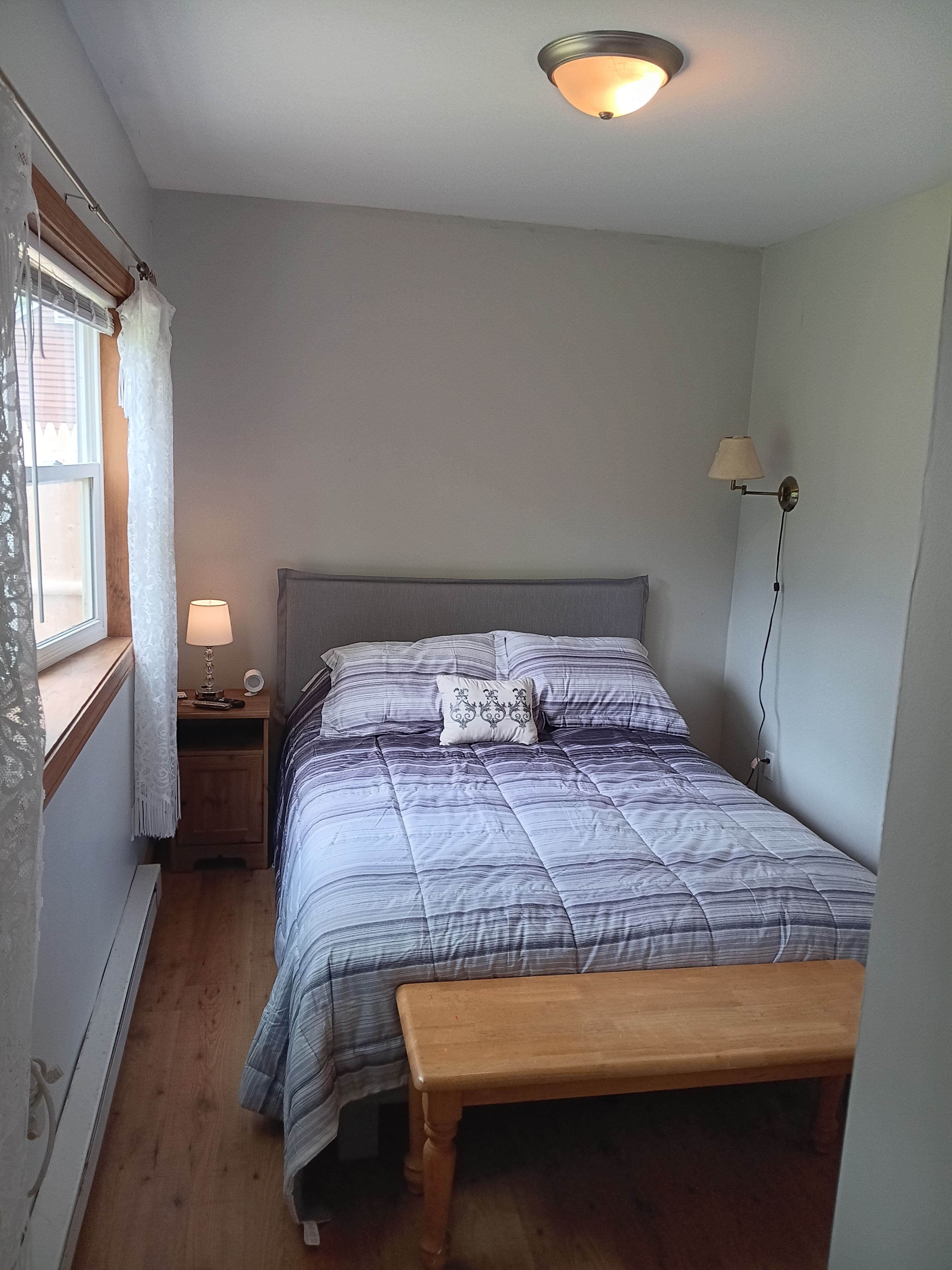Ein Schlafzimmer mit Bett, Nachttisch, Lampe und einer Bank.