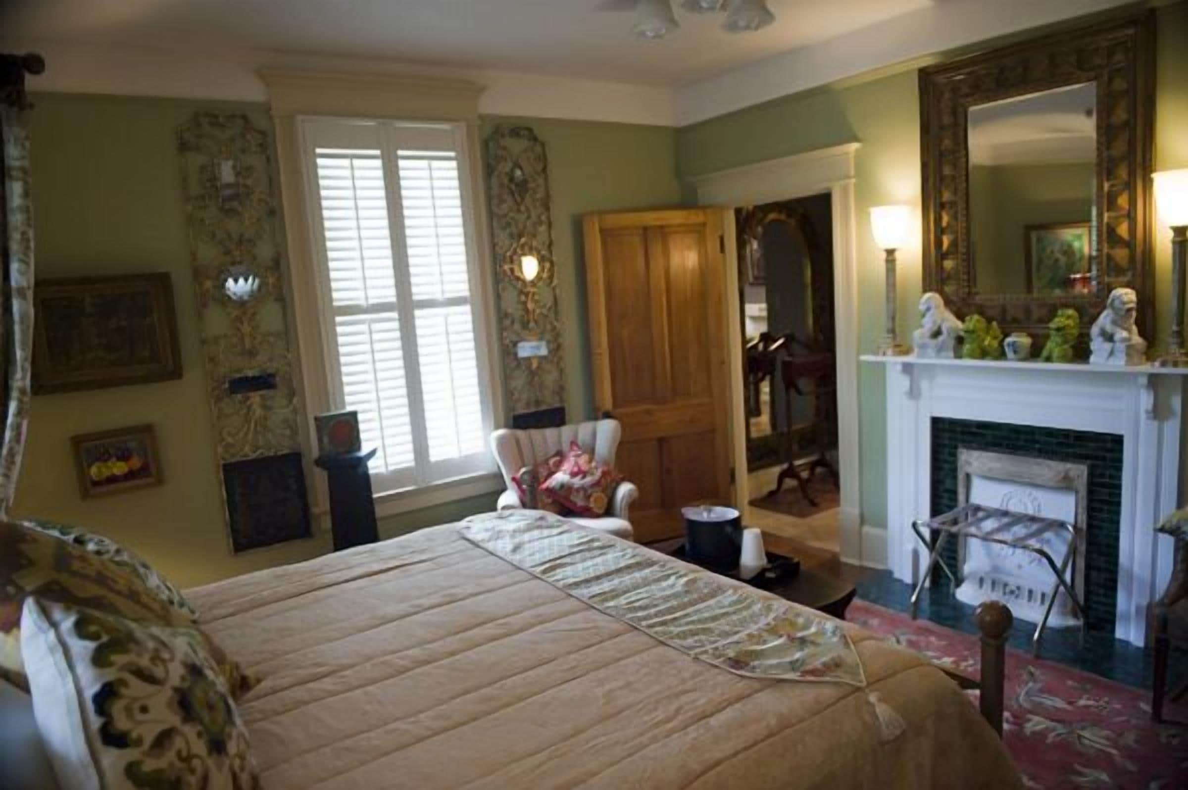 Une chambre traditionnelle avec un lit, une cheminée, un miroir et une chaise.