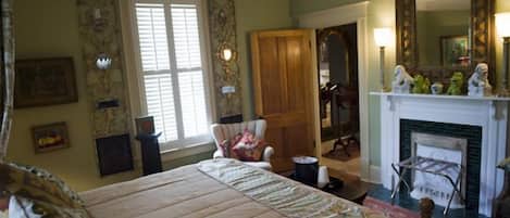 Une chambre traditionnelle avec un lit, une cheminée, un miroir et une chaise.