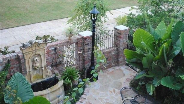 A patio with stone flooring, a brick wall, and a fountain.