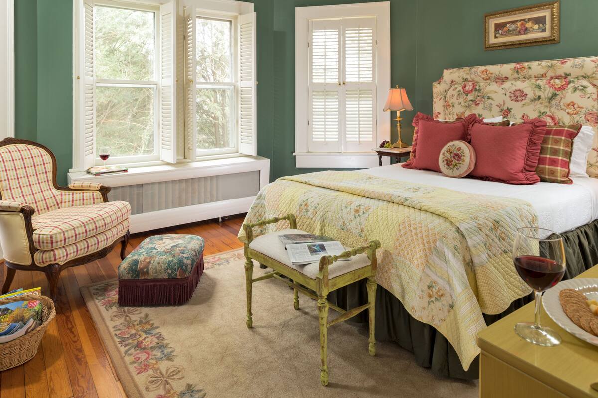 A bedroom with a bed, a chair, a table, and a window.