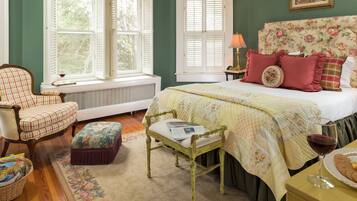 A bedroom with a bed, a chair, a table, and a window.