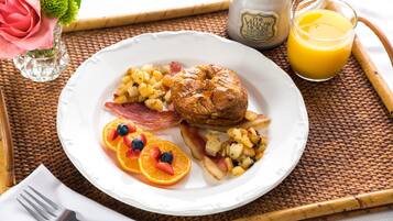 A breakfast plate with eggs, bacon, potatoes, and fruit on a woven mat.